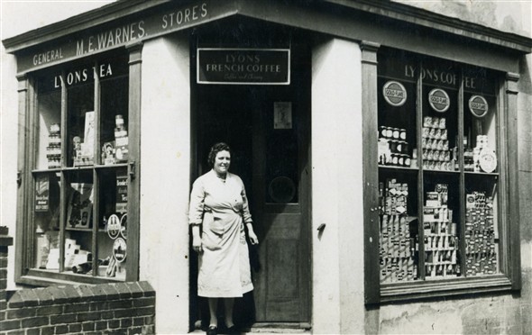 Photo:Mrs Warnes outside 'M.E. Warnes General Stores', 1 High Street. Telephone: Newhaven 299. Early 1950s