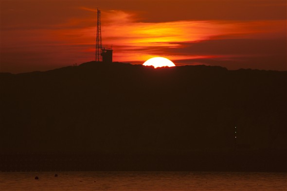 Photo:The sun dips down behind Castle Hill
